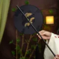 Traditional Chinese round fan for Hanfu, black bamboo handle with elegant tassel decor. - Round Farewell Waist Fan (Bamboo Edge)