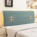 Detail shot of green quilted stretch headboard cover with elegant lace trim and embroidered pockets. - Pocket Flower Green