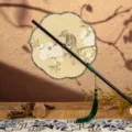Éventail rond traditionnel chinois à long manche avec imprimé floral et élégant pompon vert. - [Nouveau] Fleur de pêcher à 8 pétales avec peinture d'oiseau de montagne