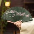 Traditional Chinese bamboo folding fan with delicate hollow carved cherry blossom patterns. - Green Cherry Blossom