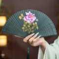 Chinese style bamboo folding fan, hollow carved design with peony painting and tassel. - Green Pink Peony