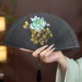 Black Chinese folding fan with hollow carved bamboo ribs and hand-painted floral art decor. - Black Ink Peony