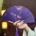 Traditional Chinese folding bamboo hand fan with elegant purple plum blossom print and tassel. - Purple Blooming Red Plum