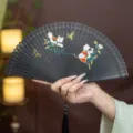 Chinese style black folding fan with carved hollow bamboo and exquisite floral butterfly painting. - Black Fluttering Butterfly