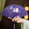 Chinese style purple bamboo folding fan with exquisite lotus painting and tassel accessory. - Purple Lotus Fragrance