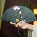 Traditional Chinese style hollow carved bamboo folding fan with elegant lotus painting and green tassel. - Green Kingfisher and Lotus