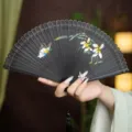 Handheld black folding hand fan with carved hollow bamboo ribs and elegant floral butterfly painting. - Black Quiet Flower and Butterfly
