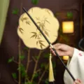 Traditional Chinese folding round fan with bamboo embroidery and elegant gold tassel charm. - 8-Petal Golden Bamboo Leaves Waist Fan (Bamboo Edge)