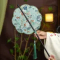 Classical Chinese bamboo folding waist fan with elegant floral embroidery and green tassel decor. - 8-Petal Koi Fish Waist Fan (Bamboo Edge)