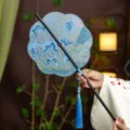 Traditional Chinese style embroidered round fan with blue floral pattern and elegant blue tassel. - 8-Petal Cyan Shirt Waist Fan (Bamboo Edge)