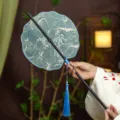 Traditional Chinese style round fan with bamboo handle, elegant blue wave pattern and tassel. - Shell Blue Ocean Waves Waist Fan (Bamboo Edge)