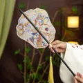 Traditional Chinese style embroidered hand fan with black handle and yellow tassel for Hanfu outfit. - Phoenix Crown Rain Butterfly Waist Fan (Bamboo Edge)