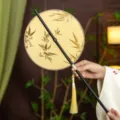 Traditional Chinese Hanfu round bamboo fan with elegant golden embroidery and tassel pendant. - Round Golden Bamboo Leaves Waist Fan (Bamboo Edge)