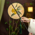 Classic Chinese round hand fan featuring loquat bird art and green tassel variant. - Round Pipat Bird Waist Fan (Bamboo Edge)
