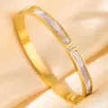 Detailed close-up of golden stainless steel bangle bracelet featuring white inlay and cubic zirconia. - DQ-2446-2