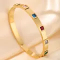 Detailed closeup of golden stainless steel bangle featuring colorful square crystal stones. - DQ-2441