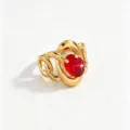 Close-up detail of a gold intertwined ring featuring a sparkling oval red zirconia. - Red Intertwined