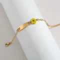 Detalle en primer plano de pulsera de acero inoxidable dorada con dije de flor esmaltada. - Mariposa Hueca (Flor Amarilla) / Color acero