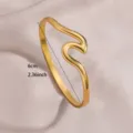 Close-up detail of the elegant gold-plated wave stainless steel open bangle bracelet. - Streamlined Geometric Wave