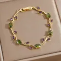 Detailed closeup of gold plated vine bracelet featuring green and purple cubic zirconia gemstones. - DQ-W-4091-1