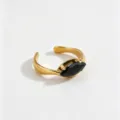 Detail view of a minimalist 18k gold plated stainless steel ring with a black marquise zircon. - Open Adjustable / Black
