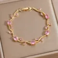 Detailed shot of gold-plated bracelet with sparkling pink cubic zirconia stones in leaf shape. - DQ-W-4092--2