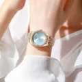Elegant gold-tone ladies quartz watch with diamond bezel and light blue dial on wrist - Blue Dial Gold Case
