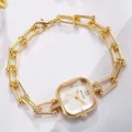 Detaillierte Makroansicht einer eleganten goldenen quadratischen Uhr mit Kugelkettenarmband - Weißes Zifferblatt Goldgehäuse