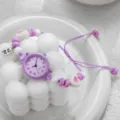 Macro view of a purple quartz watch featuring a beaded woven strap and cute heart charms - Arabic Numerals Purple