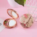 Detailed close-up view of portable double-sided folding cosmetic mirror with retro Paris print. - Car