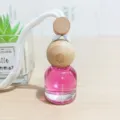 Auto Hängeparfüm Flasche mit rosa Flüssigkeit und Holzdeckel für frische Raumluft. - Begegnung