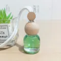 Hängender Auto-Parfumflakon aus grünem Glas mit natürlichem Holzdeckel und weißem Seil. - Gardenie