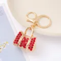 Detailopname van een stijlvolle strass handtas sleutelhanger met rode kristallen goud. - Rood