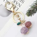 Gros plan détail d'un charmant porte-clés cerise en strass étincelant avec anneau doré. - Violet