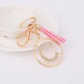 Gros plan détaillé du porte-clés lettre C en métal strass avec accessoire gland rose. - Lettre C