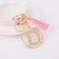 Porte-clés en métal lettre D strass avec breloque pompon rose vue de détail. - Lettre D