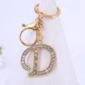 Gros plan de pendentif porte-clés lettre D en strass doré, détail de bijoux scintillants. - Lettre D