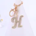 Detailed shot of gold rhinestone letter H keychain pendant, sparkling crystal charm ornament. - Letter H