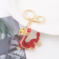 Vue détaillée du porte-clés dragon en strass, finition métal doré avec cristaux rouges vifs. - Rouge