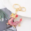 Vue de détail rapprochée du porte-clés dragon en strass scintillant avec finition or. - Rose
