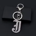 Close-up detail of silver metal rhinestone letter J keychain keyring accessory for bags. - Letter J