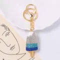 Detailed shot of sparkling rhinestone ice cream keychain with gold tone clasp on white plate. - Color 4