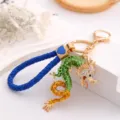 Detailed view of the Chinese zodiac dragon keychain with rhinestone embellishment and blue rope. - Green + Leather Cord