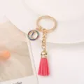 Gold metal keychain with pink leather tassel and colorful rhinestone letter L charm pendant. - L