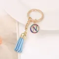 Detailed shot of a stylish gold-tone keychain with a blue tassel and a rhinestone letter N charm. - Letter N
