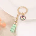 Detailed view of gold-tone keychain with green leather tassel and rhinestone letter S charm. - S