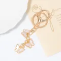 Gros plan détaillé du porte-clés doré de luxe avec breloques papillon roses et strass brillants. - Rose