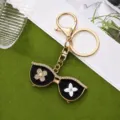 Detailed view of the luxury sunglasses keychain featuring sparkling rhinestones and gold chain. - Gold
