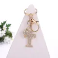 Close-up of golden rhinestone letter T keychain with crown pendant, detailed alloy charm. - Letter T