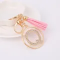 Detail shot of a sparkling rhinestone letter Q keychain with pink tassel and gold hardware. - Letter Q